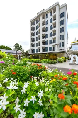 a large building with flowers in front of it at NORN Canalside Bangkok Hotel โรงแรมนอนริมคลอง in Bangkok Noi