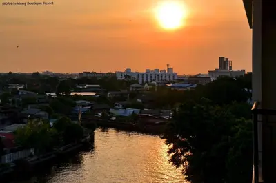 a sunset over a river in a city at NORN Canalside Bangkok Hotel โรงแรมนอนริมคลอง in Bangkok Noi