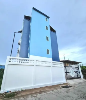 a large blue building with a white fence at The zai Apartment in Ban Krathum Lom