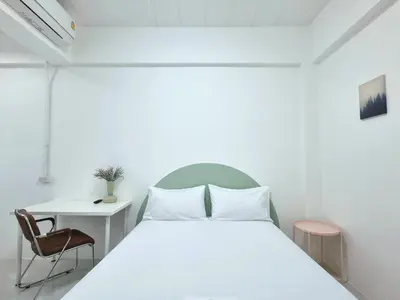 a bedroom with a white bed and a desk at The zai Apartment in Ban Krathum Lom