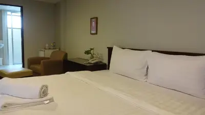a bedroom with a bed with white sheets and a chair at Mango Bedroom Inn in Bangkok