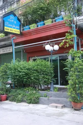 a street sign in front of a building with plants at Room For You in Bangkok