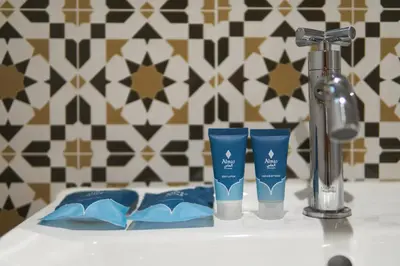 a sink with two toothbrushes and a faucet and two cups at Almas Hotel Bangkok in Bangkok