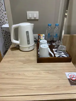a coffee maker on a counter with bottles of water at Almas Hotel Bangkok in Bangkok