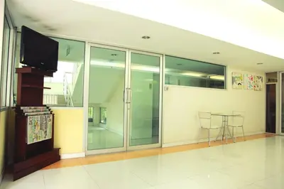 a room with a tv and a table with chairs at Mee sook Hotel and Residence in Nonthaburi