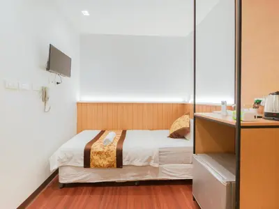 a bedroom with a bed and a desk with a television at Watergate City in Bangkok