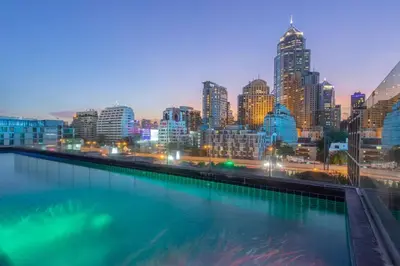 a city skyline at night with a pool of water at Hotel Icon Bangkok Sukhumvit 2 in Bangkok