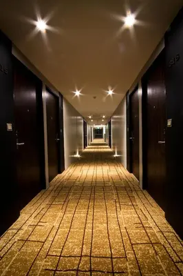an empty corridor of a building with doors and lights at Hotel Icon Bangkok Sukhumvit 2 in Bangkok