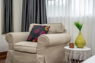 a living room with a chair and a vase at At FOUR-6 Bed, CITY CENTER, Nana BTS, MBK, Central World, Siam in Bangkok