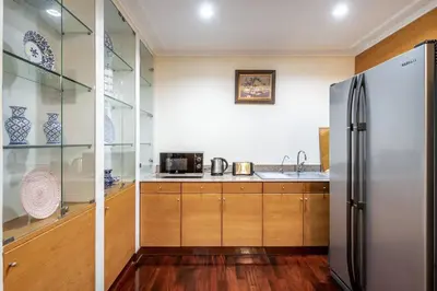 a kitchen with wooden cabinets and a refrigerator at AT NANA-5Bed, CITY CENTER, Nana BTS, MBK, Central World, Siam in Bangkok
