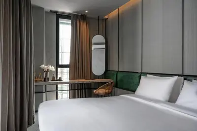 a bedroom with a large white bed and a desk at Goose Living in Bangkok