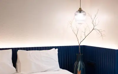 a vase with a plant in it next to a bed at karaarom hotel in Bangkok