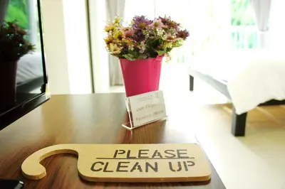 a wooden sign on a table with a vase of flowers at Wealth 30th in Bangkok