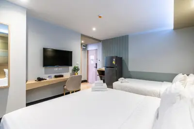 a hotel room with two beds and a flat screen tv at Hi Sotel Victory Monument in Bangkok