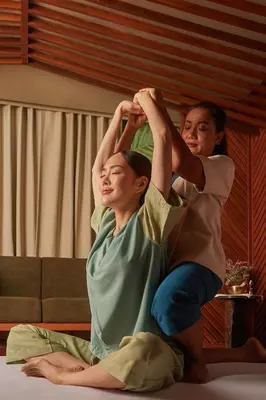 two women sitting on a bed with their hands in the air at The Salil Hotel Riverside Bangkok in Bangkok