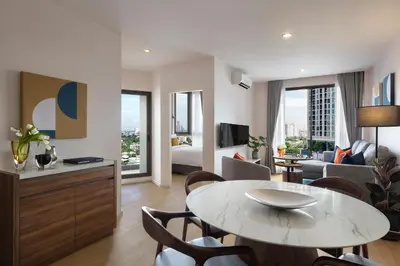 a living room with a table and a living room with a bed at Oakwood Suites Tiwanon Bangkok in Nonthaburi
