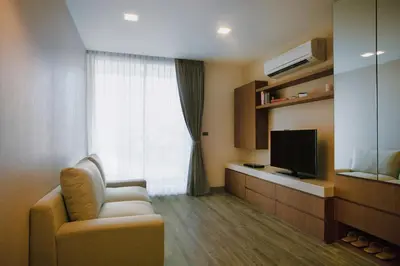 a living room with a chair and a television at Olive Hotel Bangkok 64 in Bangkok