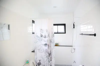 a white bathroom with a shower with a shower curtain at SLEEP SLEEP SUANPHAK Homestay in Ban Khlong Bang Sai