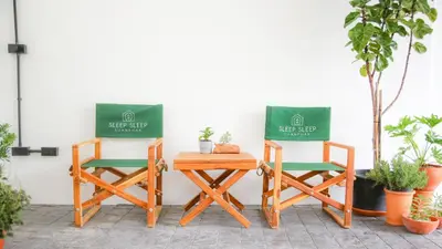 two chairs and a table next to a white wall at SLEEP SLEEP SUANPHAK Homestay in Ban Khlong Bang Sai