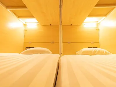 two white beds in a room with wooden walls at Khao San Social Capsule Hostel in Bangkok