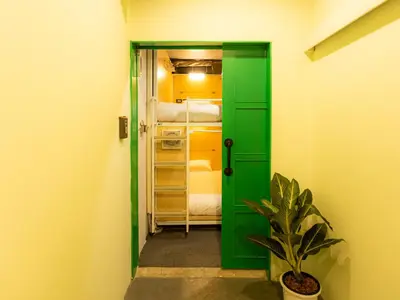 a green door leading into a room with a bedroom at Khao San Social Capsule Hostel in Bangkok
