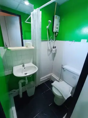 a green bathroom with a toilet and a sink at Room@Doze in Nonthaburi