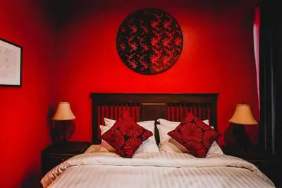 a bedroom with red walls and a bed with pillows at Caiyong Hometel & Cafe's Studio in Khlong San