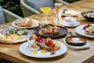 a wooden table with plates of breakfast food on it at Ad Lib Hotel Bangkok in Bangkok