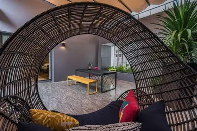 a living room with a wicker chair and a table at Ad Lib Hotel Bangkok in Bangkok
