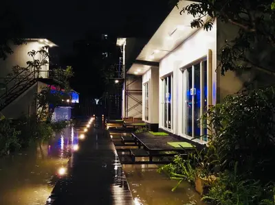 a rain soaked street at night with a building at Wild Ones Hostel in Bangkok