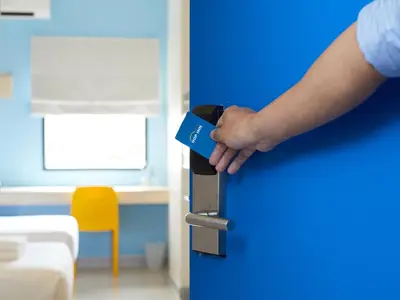 a person holding a blue door with their hand at HOP INN Bangkok Bangna in Bangkok