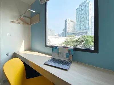 a laptop computer sitting on a wooden desk with a window at HOP INN Bangkok Onnut Station in Bangkok