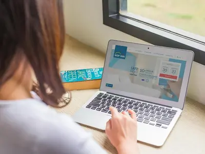 a woman sitting at a table using a laptop computer at HOP INN Bangkok Onnut Station in Bangkok