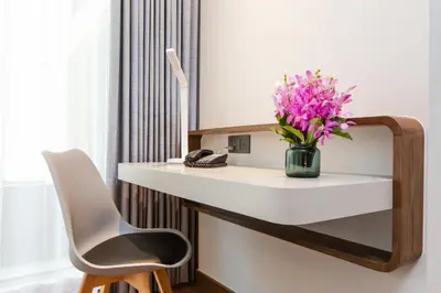 a white desk with a vase of flowers on it at Centara Life Hotel Bangkok Phra Nakhon in Bangkok