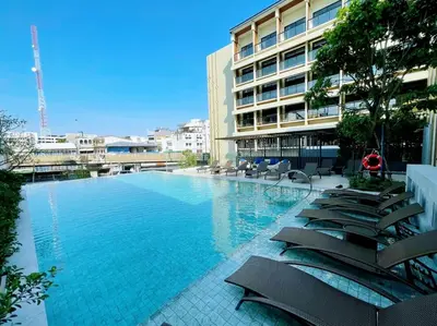 a large swimming pool with chairs and a building at Centara Life Hotel Bangkok Phra Nakhon in Bangkok