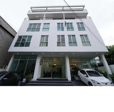 a white building with cars parked in front of it at RQ Bangkok Sukhumvit 50 by Collection O in Amphoe Phra Khanong