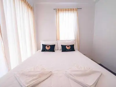 a white bed with two pictures of two people on it at RQ Bangkok Sukhumvit 50 by Collection O in Amphoe Phra Khanong