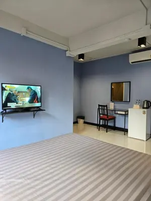a bedroom with a tv on a blue wall at HOUSEMODE - BAANYAI @ Wongwian Yai in Bangkok