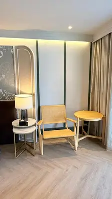 a room with a chair and two tables and a lamp at The Quarter Chaophraya by UHG in Bangkok