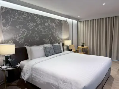a bedroom with a large white bed and a black wall at The Quarter Chaophraya by UHG in Bangkok