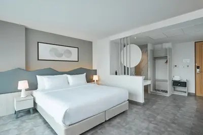 a bedroom with a large white bed and a bathroom at Livable Hotel Bangkok in Bangkok
