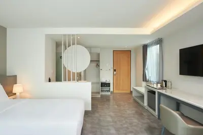 a bedroom with a bed and a desk with a television at Livable Hotel Bangkok in Bangkok