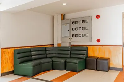 a green leather couch in a room with a clock on the wall at Latin Garden Hotel in Bangkok