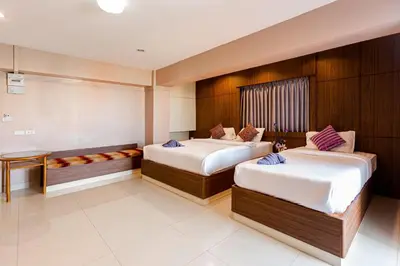 a hotel room with two beds and a bench at Latin Garden Hotel in Bangkok
