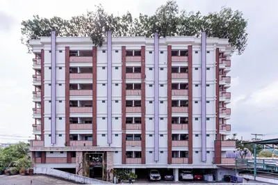 a building with a tree on top of it at Latin Garden Hotel in Bangkok
