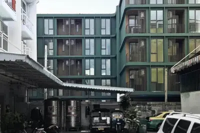 a tall green building with cars parked in front of it at POP Heritage Residence in Bangkok