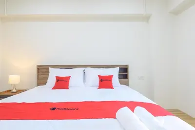 a large white bed with red pillows on it at Hoenhao Boutique Ratchada in Bang Su