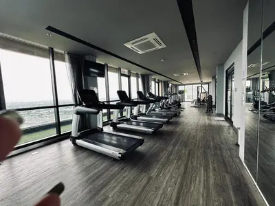 a gym with a row of treadmills and windows at Plum central westgate@Bangyai in Ban Bang Krabu
