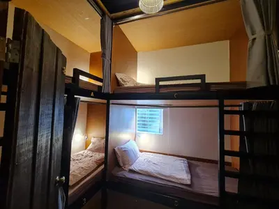 two bunk beds in a room with a window at Non House Bangkok บ้านนอนโฮสเทล in Bangkok