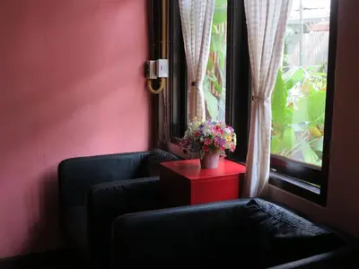 a room with two chairs and a window with flowers at Non House Bangkok บ้านนอนโฮสเทล in Bangkok